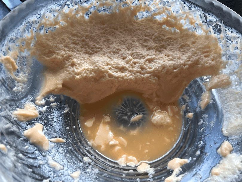 A grim scene of beige / orange foamy pudding clinging to a cut-glass bowl, gross watery stuff in the bottom. 