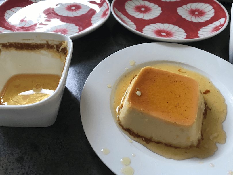 A ramekin with a layer of shiny golden stuff in the bottom, next to a plate holding a square custard swimming in golden liquid.