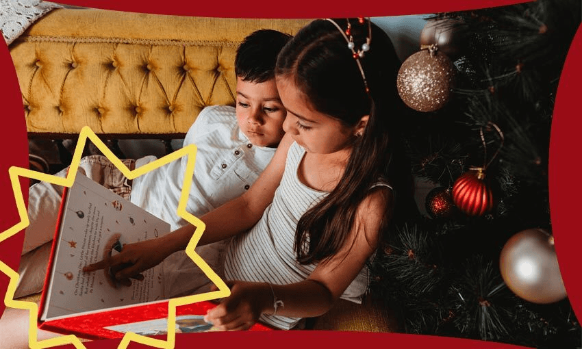 Two kids on a couch, Christmas tree beside them, reading a book.