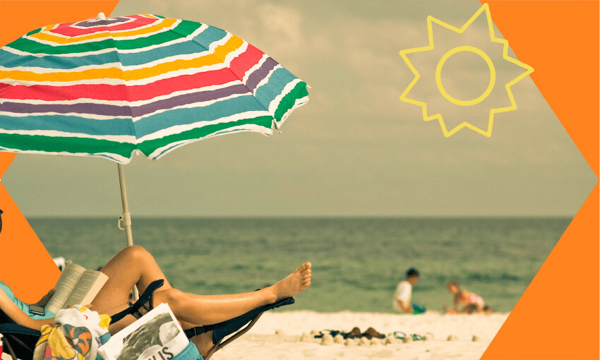 Beach scene, kids playing at the water's edge, person on deck chair reading.