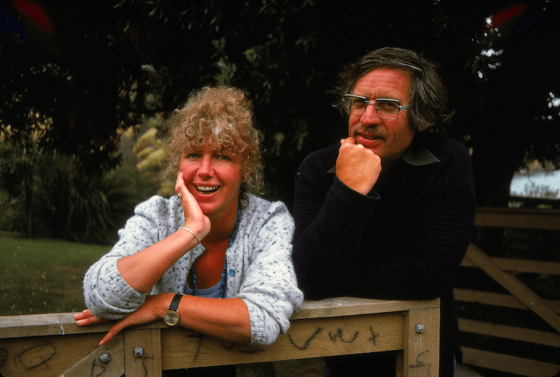 Colour photograph of middle-aged couple leaning over a wooden gate, both happy, the woman energetically so.