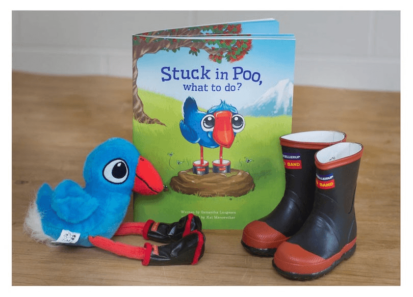 Photo of a picture book flanked by a plush toy pūkeko wearing Red Bands, and a pair of kids' Red Bands. 