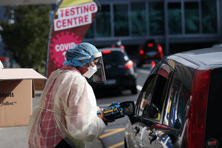 A health worker hands out rapid antigen tests at a testing centre in West Auckland on February 24 (Photo: Fiona Goodall/Getty Images) 
