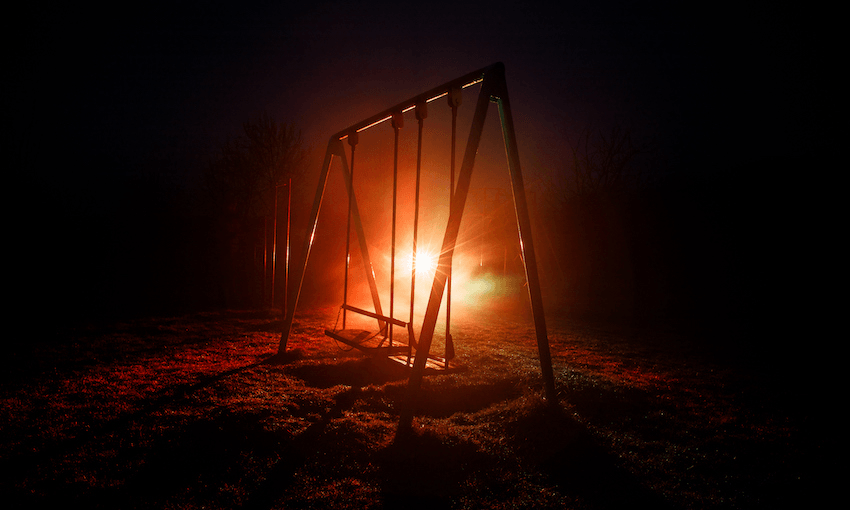 Night photo of metal swing with car light behind