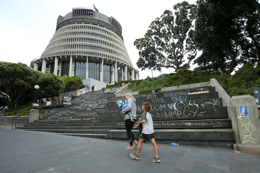 WELLINGTON, NEW ZEALAND – FEBRUARY 23: People walk past graffiti covered steps during a protest at Parliament on February 23, 2022 in Wellington, New Zealand. The perimeter of the anti-vaccine and COVID-19 mandate protest is slowly being reduced by police after sixteen days of demonstrations on and around the grounds of Parliament. (Photo by Hagen Hopkins/Getty Images) 
