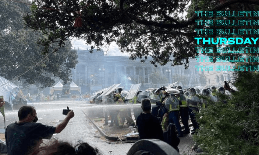 Firefighters are covered by riot shields to protect them from projectiles as they put out blazes on the parliament grounds. (Image: RNZ)
