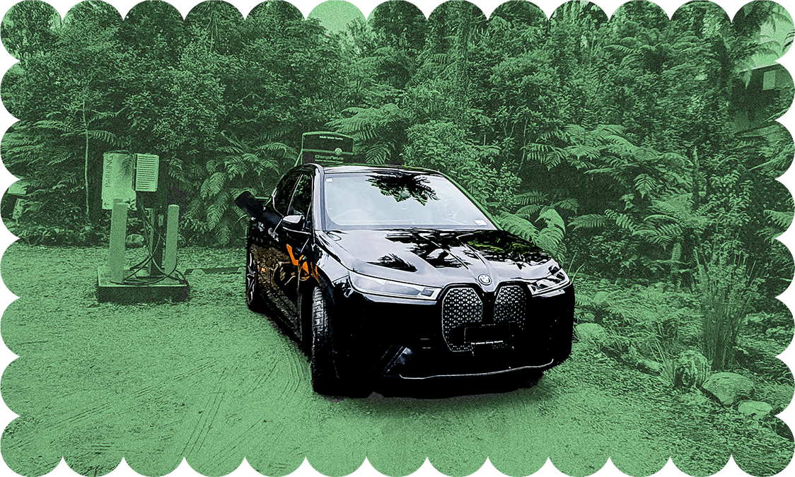 An iX in its natural habitat, charging at Franz Josef (Photo: Don Rowe; Additional design: The Spinoff) 
