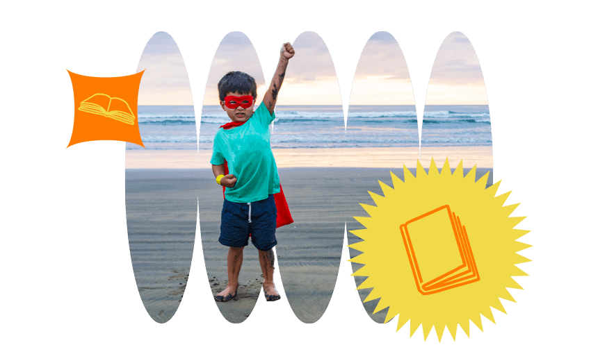 Young boy in superhero costume on beach, one triumphant fist punching the sky.