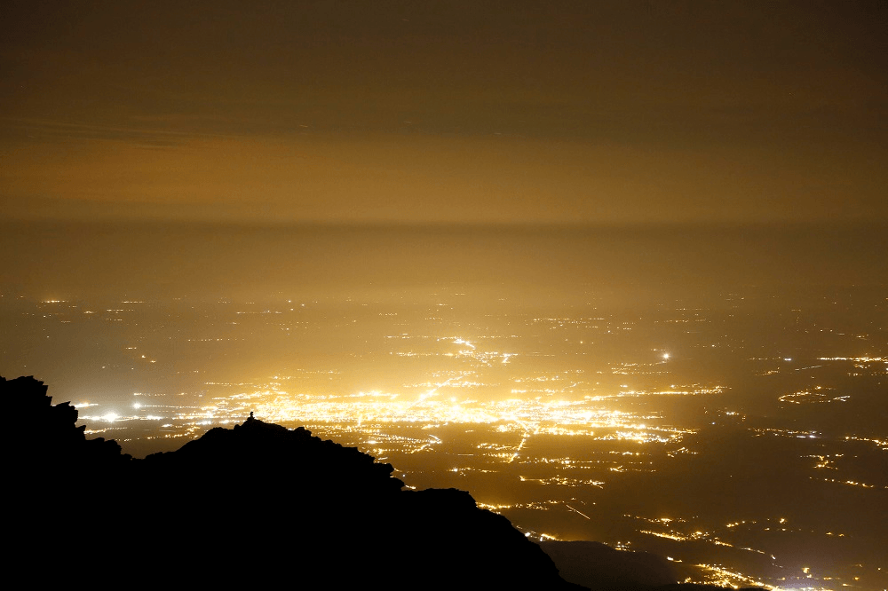hazy yellow light pollution rises from a city obscuring the sky