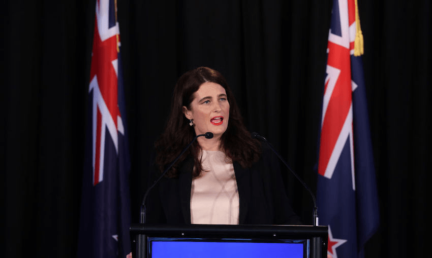 white woman with dark hair next to NZ flags
