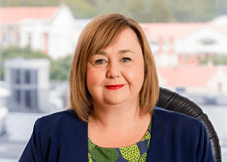 a white woman with medium brown hair in a bob and houses behind here