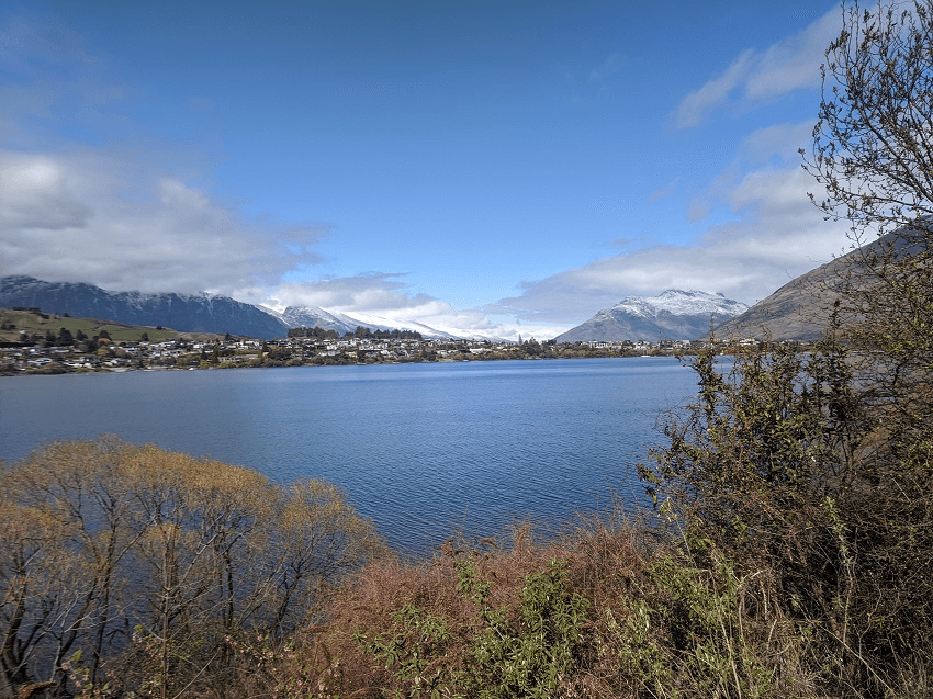 blue lake mountains and some buildings on the other side of the water