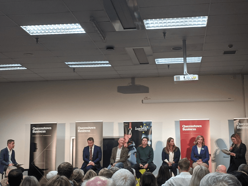 five candidates sit in front of queenstown business signs