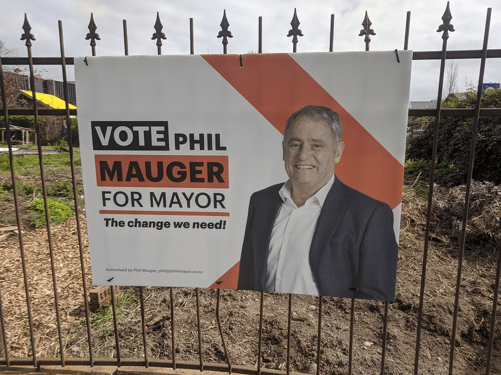 An election billboard with phil major (white man in suit) on it. background is a fence