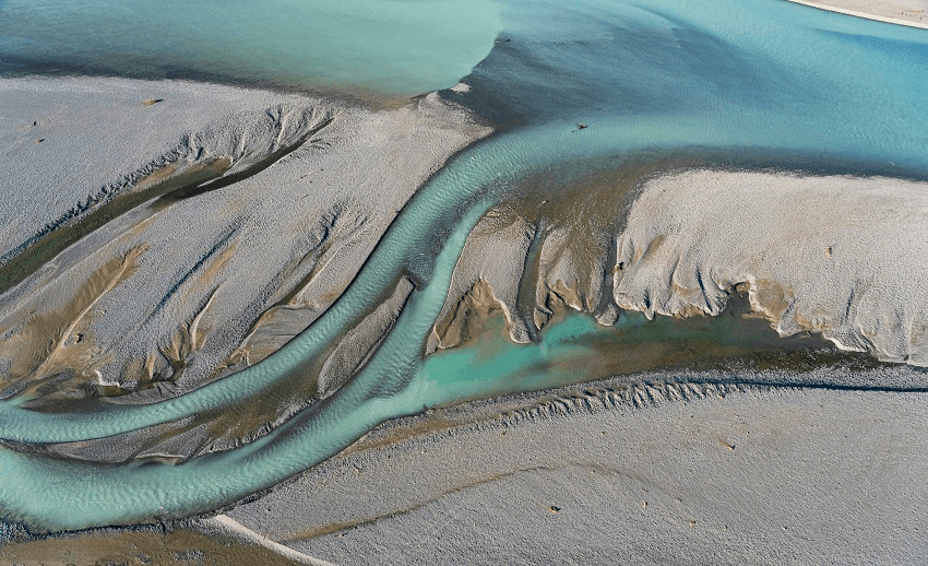 a broad blue river from above, twisted strands and gravel