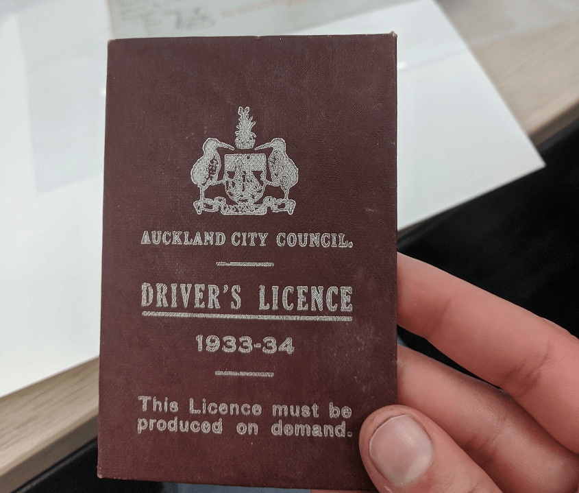 Shanti's hand holds a brown leather folder with a kiwi logo and the words "Auckland City Council Driver's licence 1933-34'