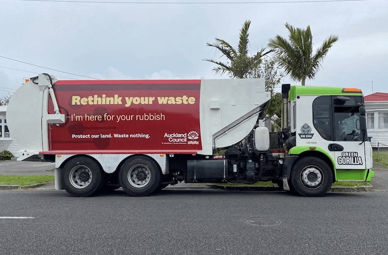a rubbish truck with a red sign reading "rethink your waste" on it