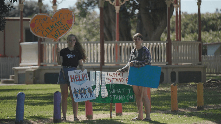 two climate protesters young people with signs in the town of Thames