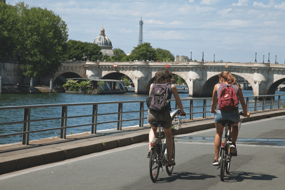 Two bikes along the river Seine in Paris with the Eiffel Tower in the background.