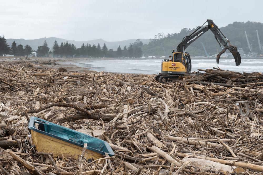 Heavy equipment starts to clear a beach of logs and debris in Gisborne. (Photo: Getty) 
