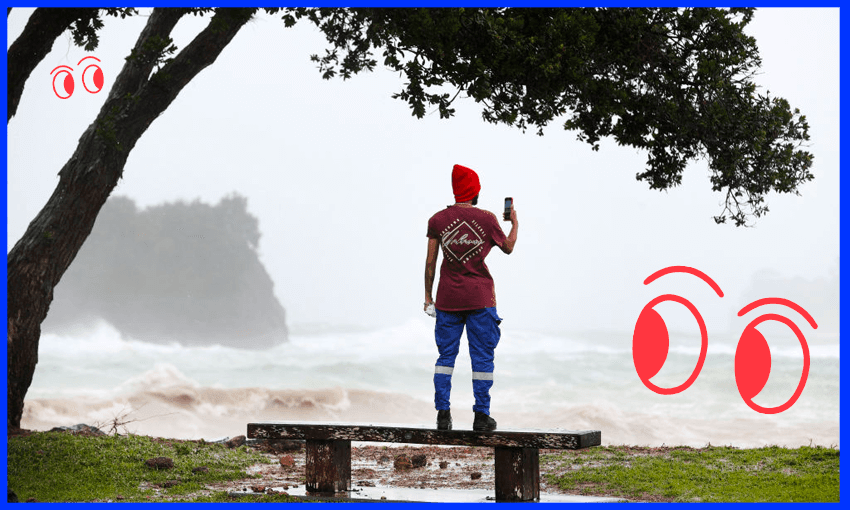 A punter grabs some cellphone footage on Matheson Bay Beach in Matakana during Cyclone Gabrielle. (Photo: Fiona Goodall/ Getty Images)
