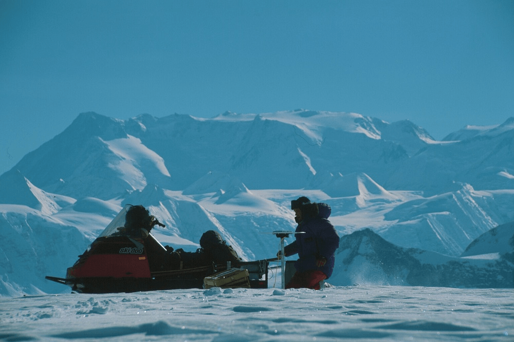 grainy hazy sorta vintage vibes of BIG OLD mountains and ice ice ice and a silohetted figure with a skidoo