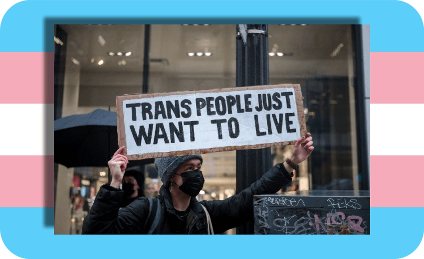 A person holds a sign reading "Trans People Just Want to Live"