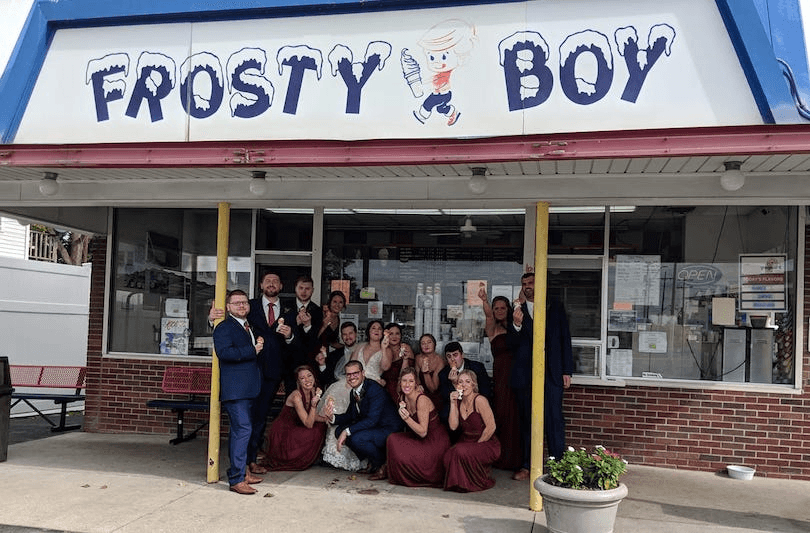 A group of people huddle under a Frosty Boy sign in Michigan