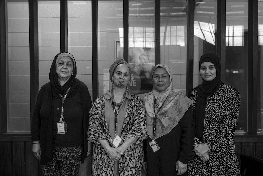 Black and white photo of four women in headscarves and wearing lanyards