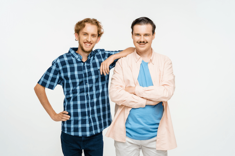 Two friends stand next to each other, smiling at the camera