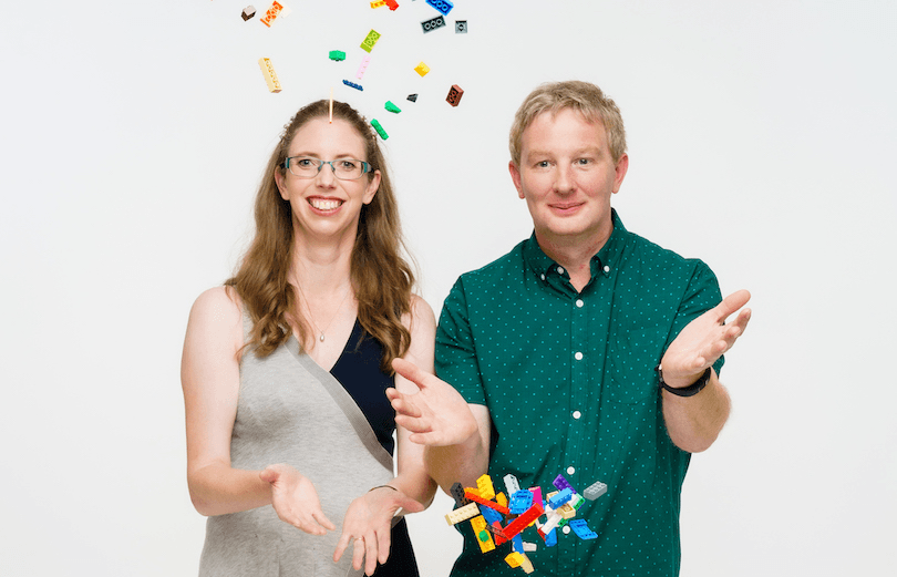 A man and woman throw Lego bricks into the air and smile