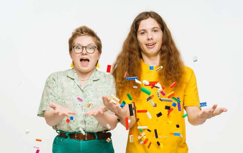 Siblings stand and throw Lego pieces into the air