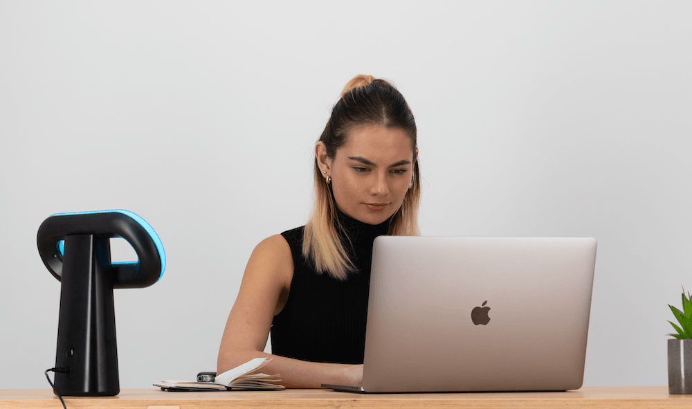 A blue desk lamp on the desk of an office worker.