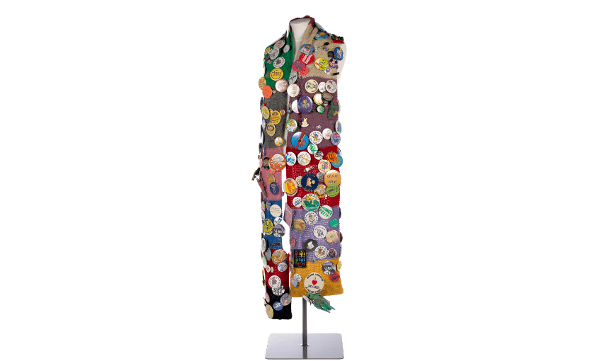 A photo of a scarf with a lot of different badges pinned to it.
