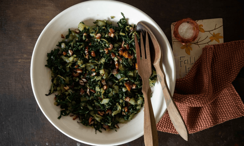 Sauteed silverbeet with date and onion in a serving bowl with wooden servers