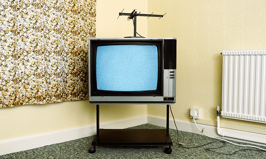 An old TV showing static in a yellow room with paisley curtains and a gas heater on the wall