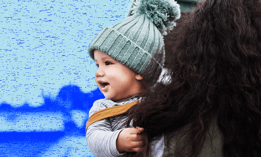 A small child in a beanie is held by a woman with long dark hair