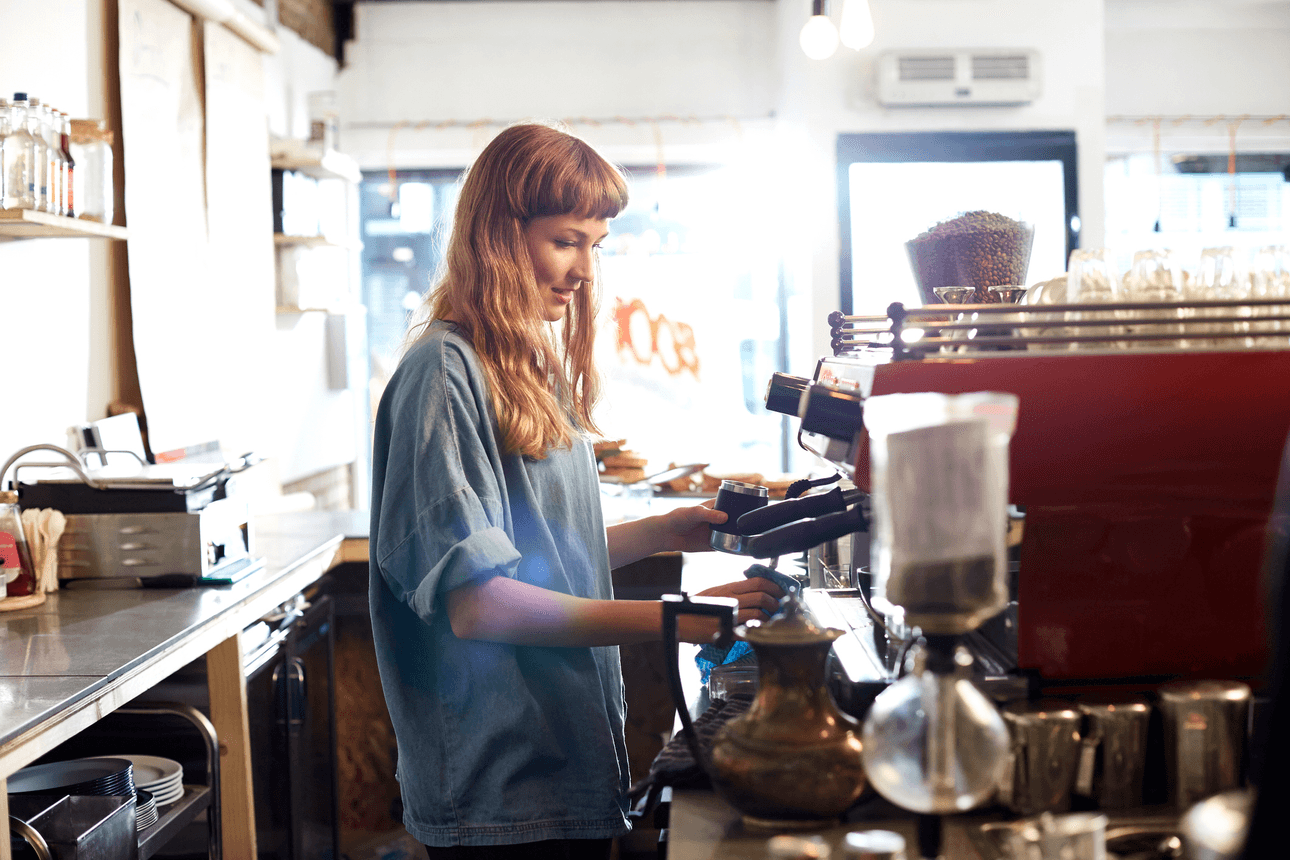 a woman with long hair making coffee in a cafe