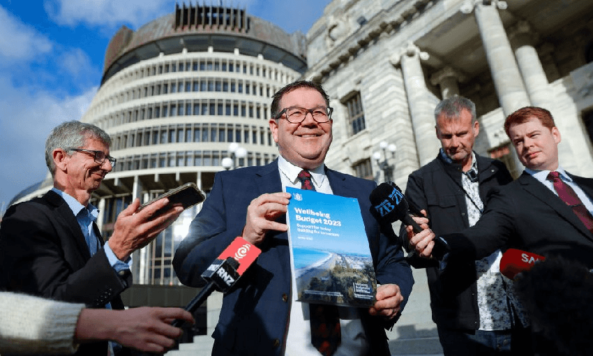 Grant Robertson speaks to media while holding a copy of Budget 2023 (Photo by Hagen Hopkins/Getty Images) 
