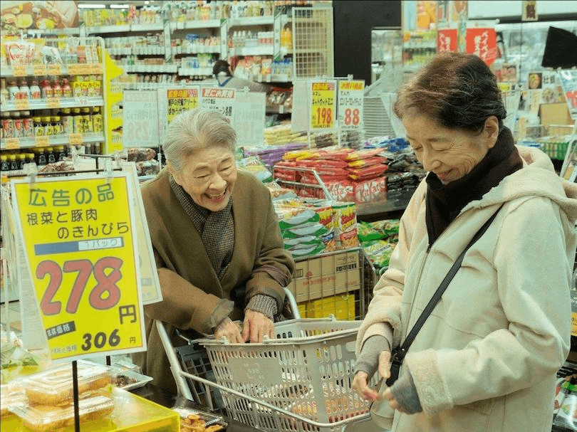 two elderly Japanese women laughing while shopping for groceries