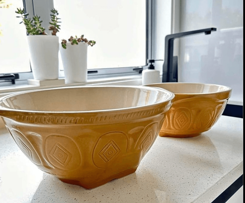 two yellow ceramic bowls on a well lit kitchen bench 