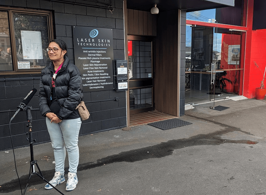 a woman wearing jeans and a puffer jacket standing in a carpark