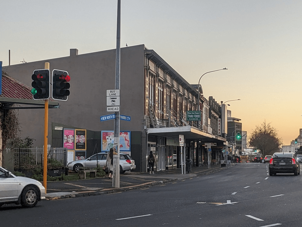 late evening with a yelow sky, a road with some buildings and cars