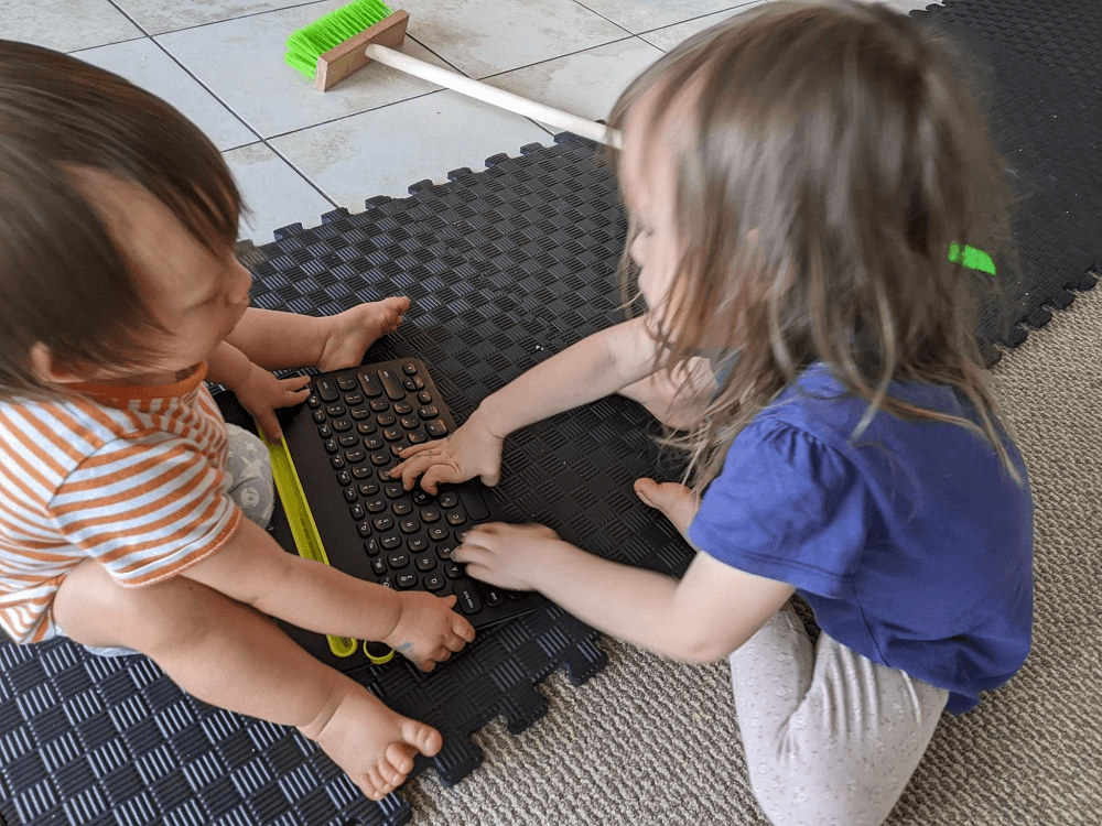 two little kids sitting on plastic flooring playing with each others