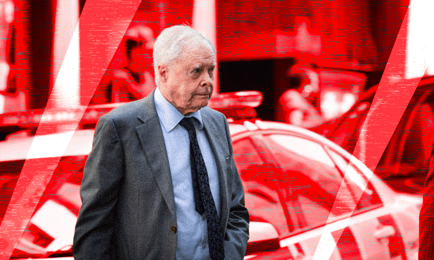 An elderly man in a suit in front of a police car. The background has a red filter