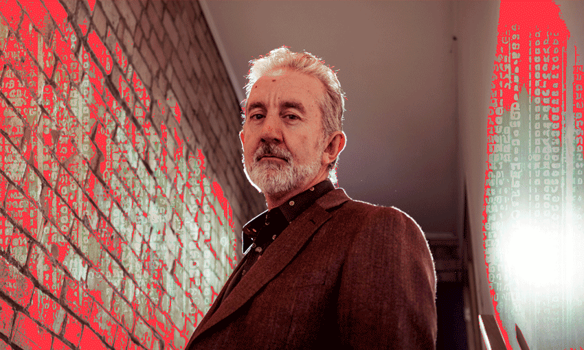 Nigel Latta looking scammy next to a brick wall. Photograph shot from a weirdly low angle