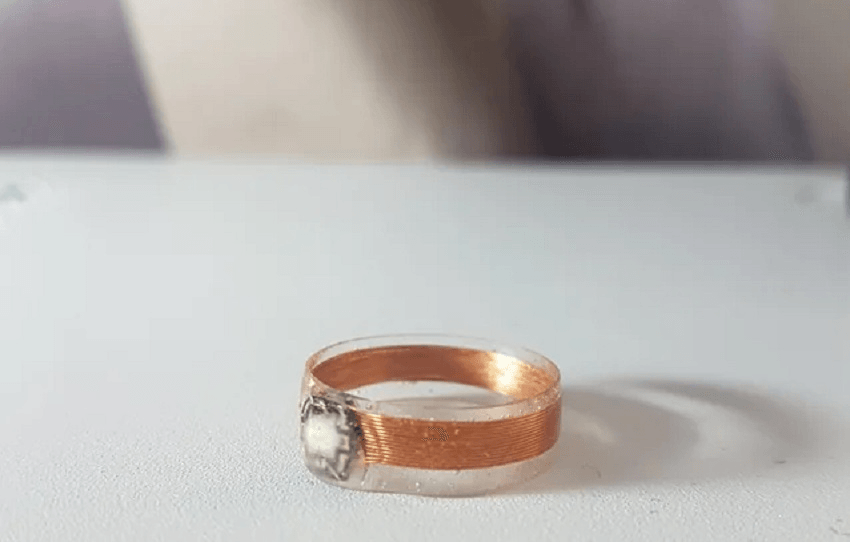 a clear plastic ring on a grey table with a copper coil inside