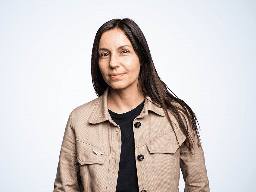 a romanian woman wearing a tan jacket with long brown hair