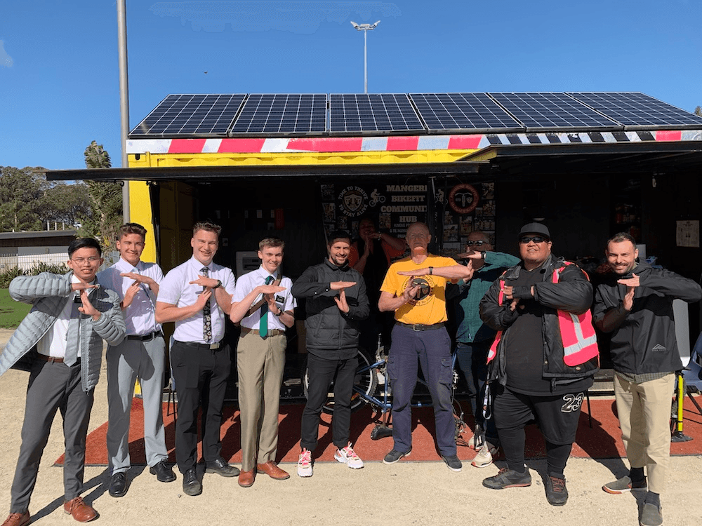 Mormon missionaries, Triple Teez kaimahi and AT staff pull a T outside the Māngere bike hub.