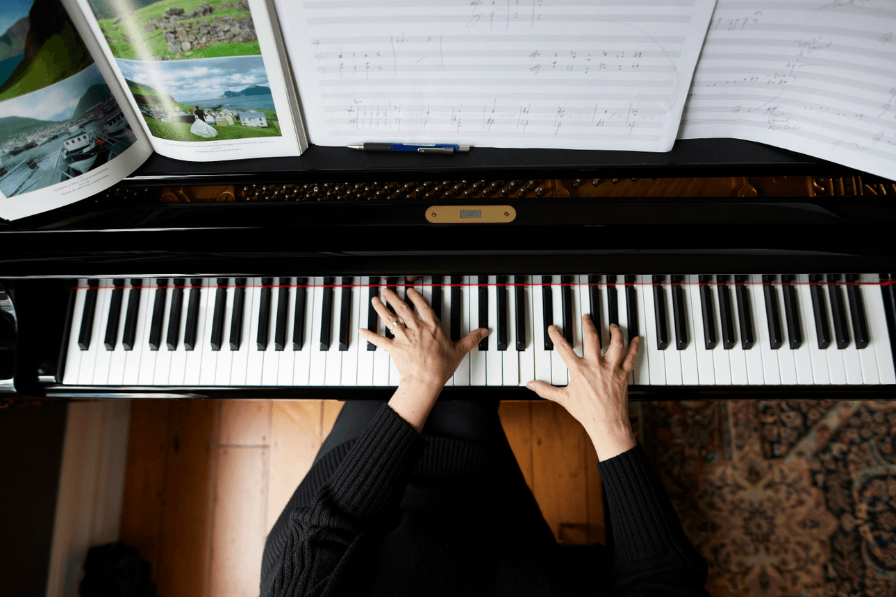 A top-down photograph of composer Victoria Kelly's hands playing a grand piano